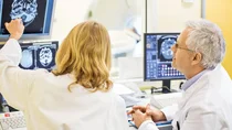 Epilepsie: Eine &Auml;rztin und ein Arzt begutachten das gescannte Bild eines Sch&auml;dels und Gehirns auf einem Monitor.