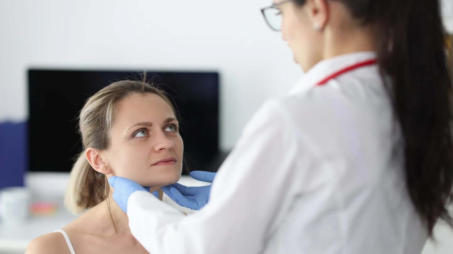 &Auml;rztin tastet die Bereiche der Unterkieferspeicheldr&uuml;se einer Patientin ab.