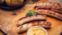 Erh&ouml;hte Cholesterinwerte: Auf einem Holzbrett liegen frisch gegrillte Bratw&uuml;rste.