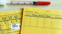Zwei aufgeschlagene Impfausweise, davon einer mit eingetragener Impfung gegen Mumps, Masern und Röteln.