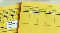 Zwei aufgeschlagene Impfausweise, davon einer mit eingetragener Impfung gegen Mumps, Masern und Röteln.