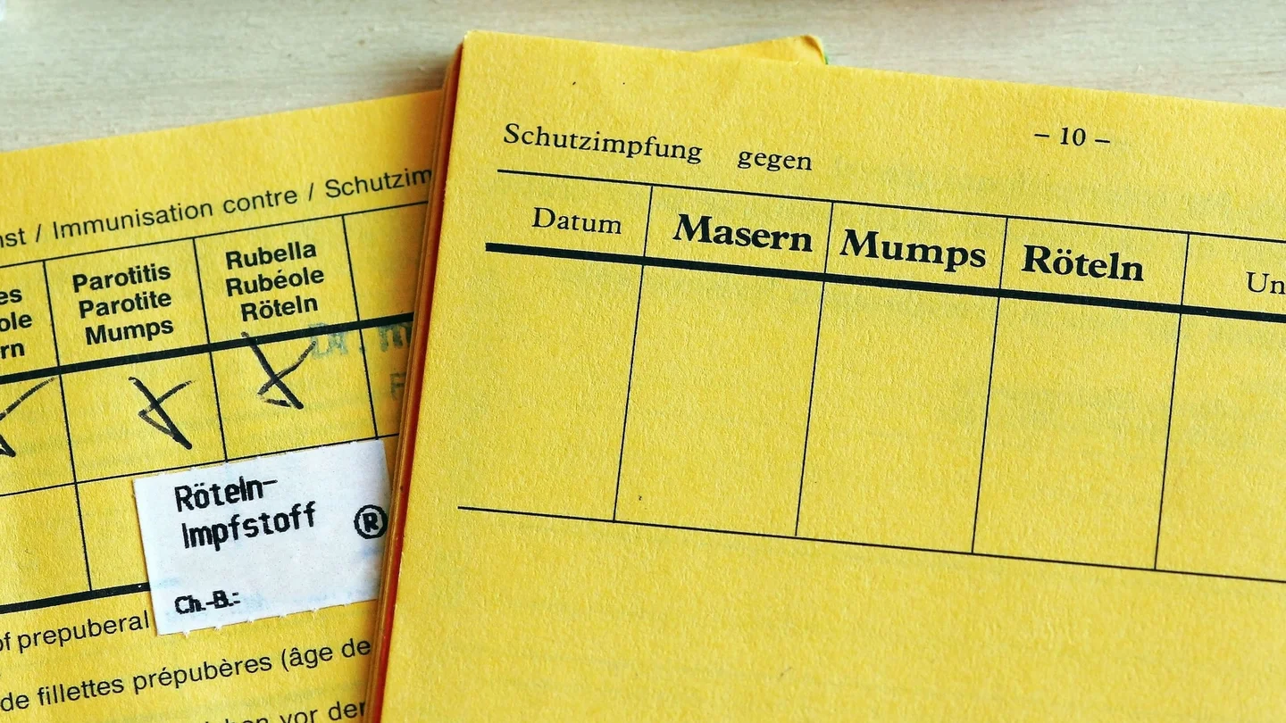 Zwei aufgeschlagene Impfausweise, davon einer mit eingetragener Impfung gegen Mumps, Masern und Röteln.