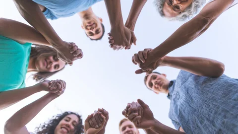 Menschen stehen im Kreis und halten sich an den Händen.