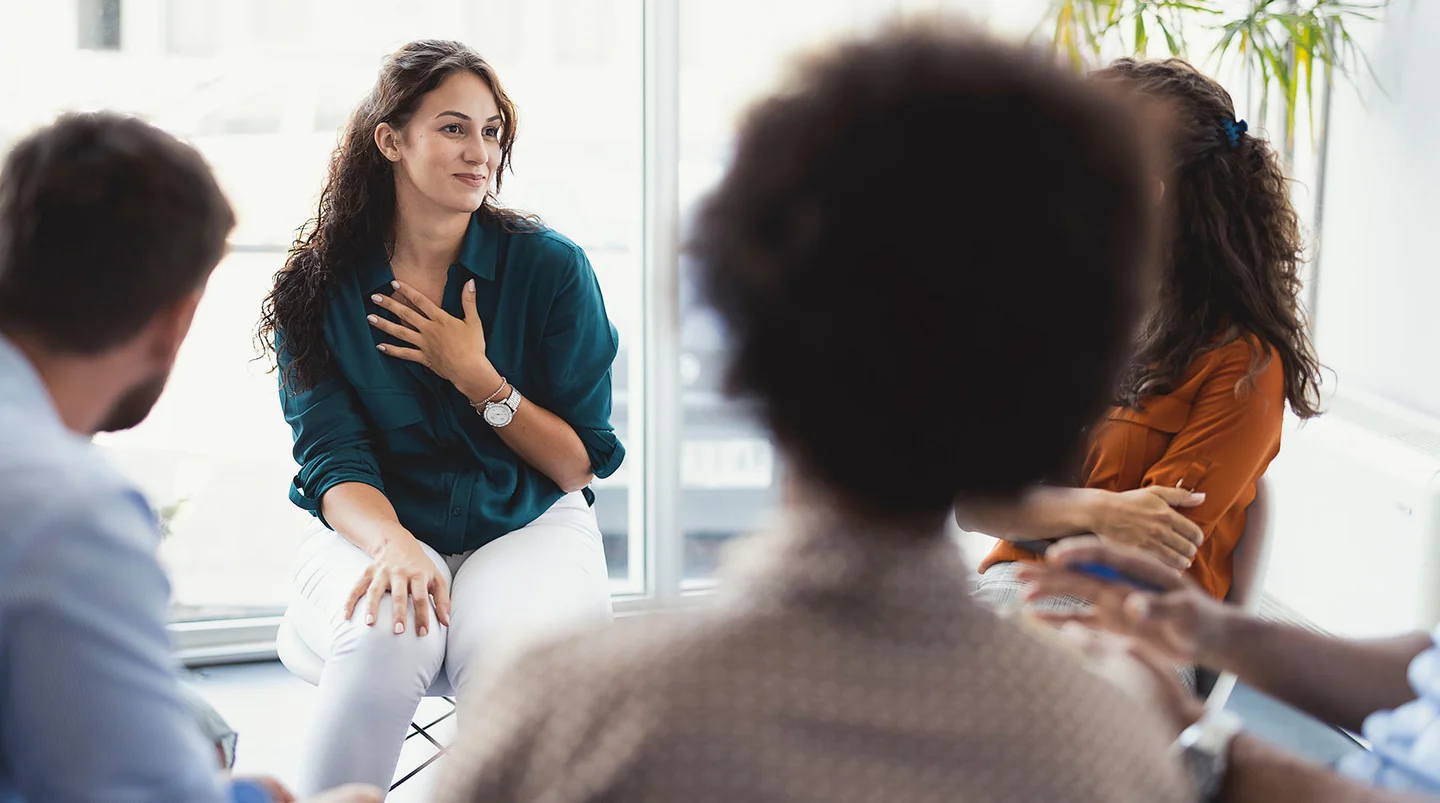 Frau sitzt in kleiner Gesprächsrunde