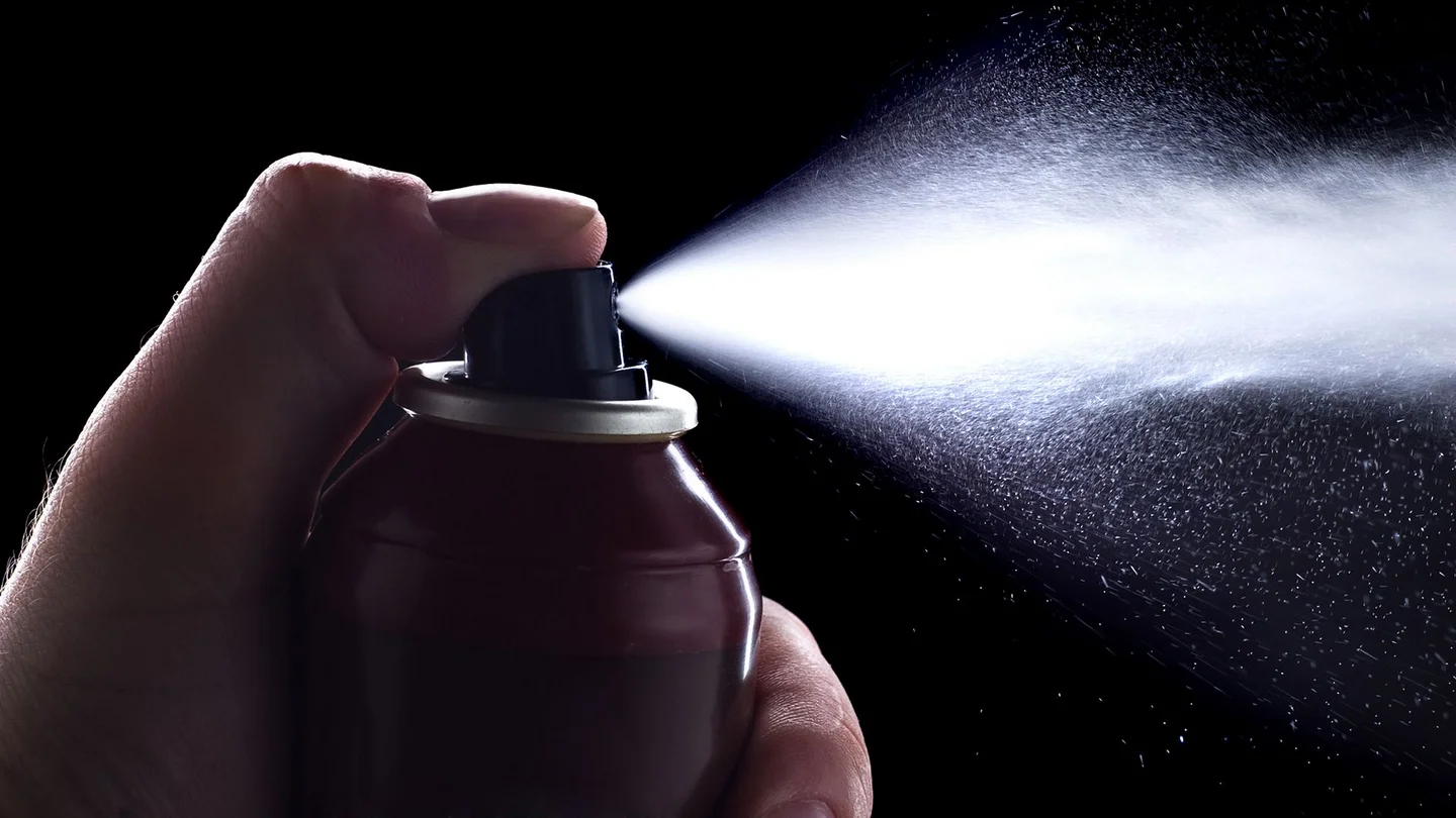 Kontakt-Allergie: Ein Daumen dr&uuml;ckt auf den Ausl&ouml;ser eines Kontaktsprays - Spray tritt aus.