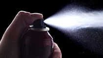 Kontakt-Allergie: Ein Daumen dr&uuml;ckt auf den Ausl&ouml;ser eines Kontaktsprays - Spray tritt aus.